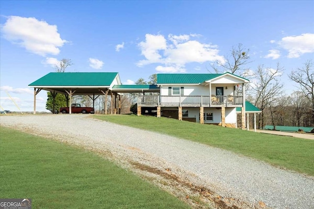 view of front facade featuring a porch, a front yard, metal roof, and driveway