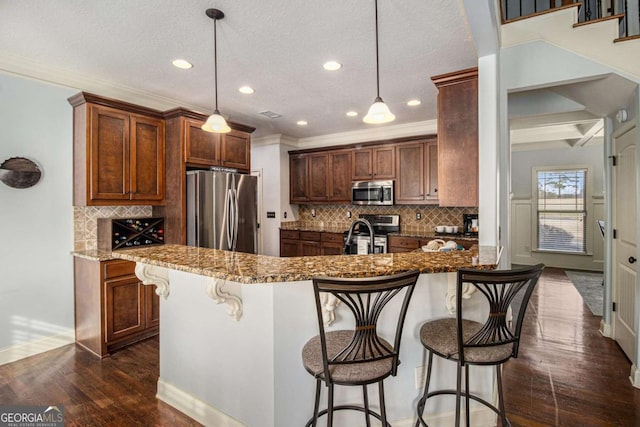 kitchen with a breakfast bar area, stone countertops, dark hardwood / wood-style flooring, pendant lighting, and stainless steel appliances