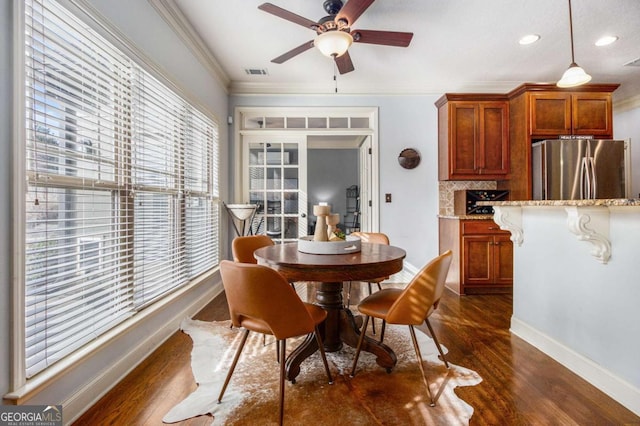 dining space with crown molding, dark wood-type flooring, and ceiling fan