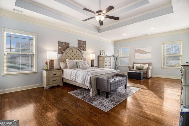 bedroom featuring crown molding, dark hardwood / wood-style floors, ceiling fan, and a tray ceiling