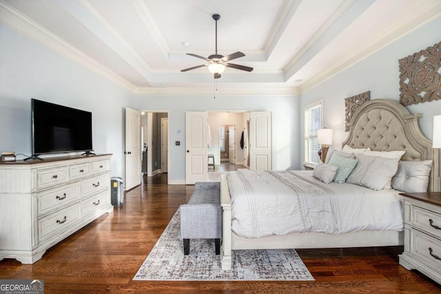 bedroom with crown molding, dark wood-type flooring, ceiling fan, and a tray ceiling