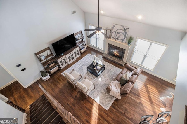 living room with dark hardwood / wood-style floors, ceiling fan, a fireplace, and vaulted ceiling