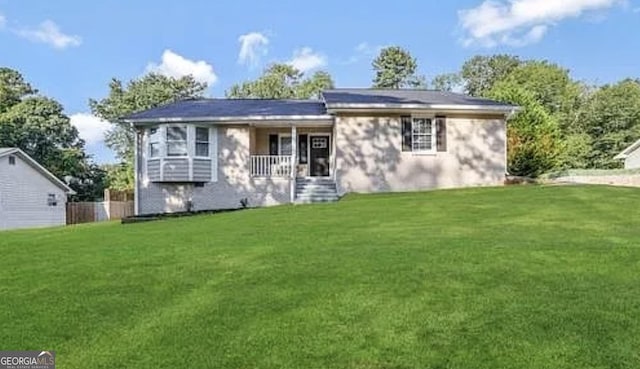 rear view of house featuring covered porch and a lawn