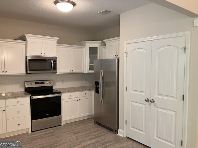 kitchen featuring light stone countertops, white cabinetry, and appliances with stainless steel finishes