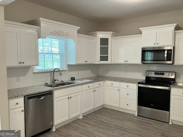 kitchen featuring dark wood-type flooring, sink, white cabinetry, tasteful backsplash, and appliances with stainless steel finishes