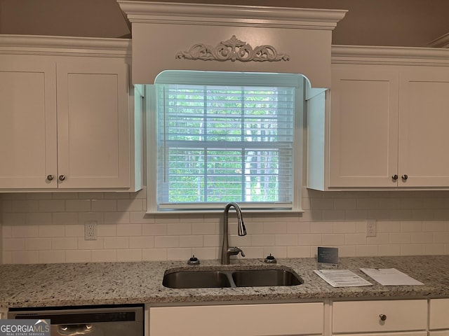 kitchen with white cabinetry, stainless steel dishwasher, sink, and light stone counters