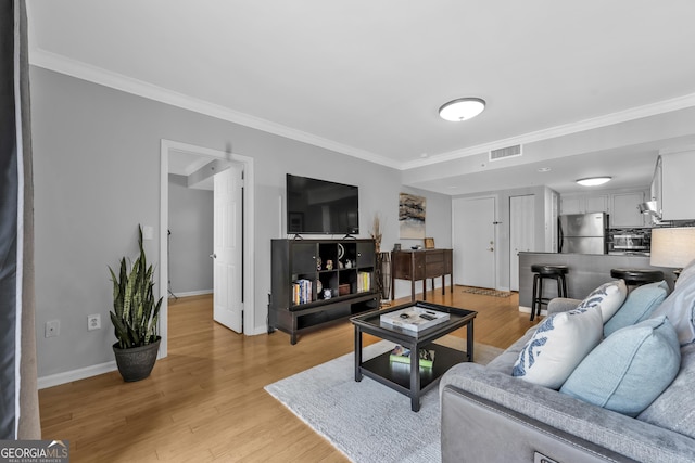 living room featuring light wood finished floors, baseboards, visible vents, and ornamental molding