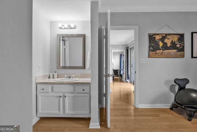 bathroom featuring crown molding, vanity, baseboards, and wood finished floors