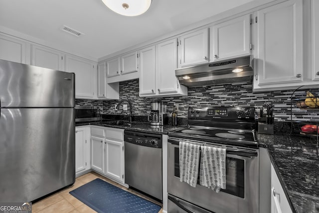 kitchen featuring light tile patterned floors, stainless steel appliances, dark stone counters, and white cabinets