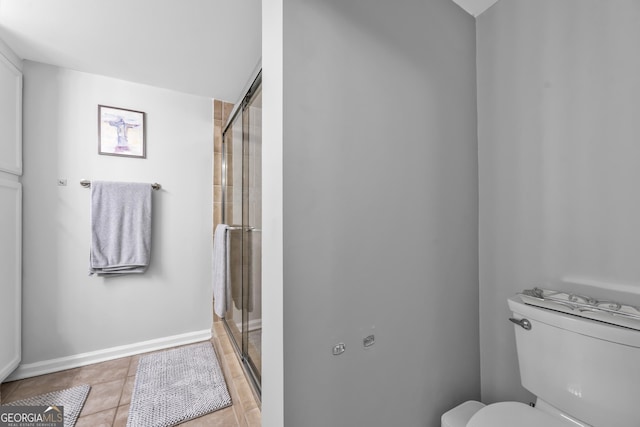 full bath featuring a stall shower, tile patterned flooring, toilet, and baseboards