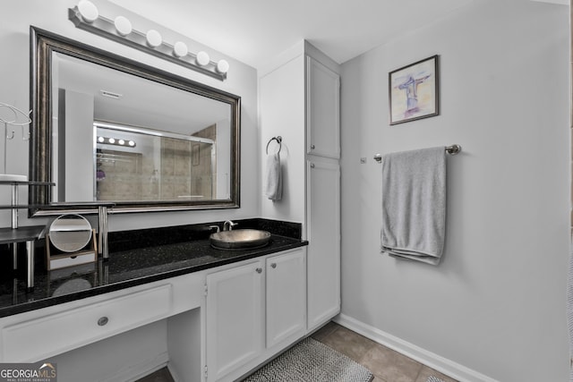 full bathroom featuring tile patterned flooring, baseboards, a tile shower, and vanity