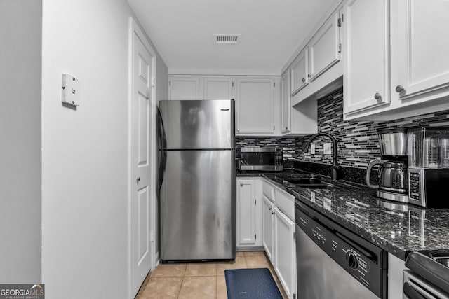 kitchen featuring dark stone countertops, white cabinets, and appliances with stainless steel finishes