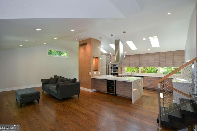 kitchen with vaulted ceiling with skylight, island range hood, decorative light fixtures, dark hardwood / wood-style floors, and beverage cooler