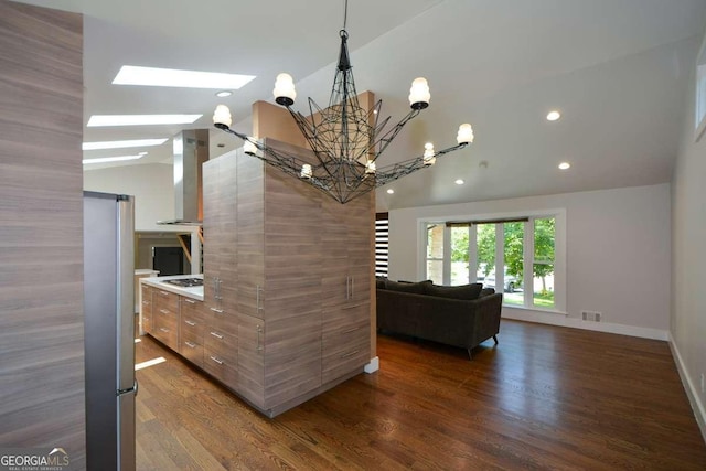 kitchen featuring lofted ceiling, dark wood-type flooring, wall chimney range hood, and gas cooktop