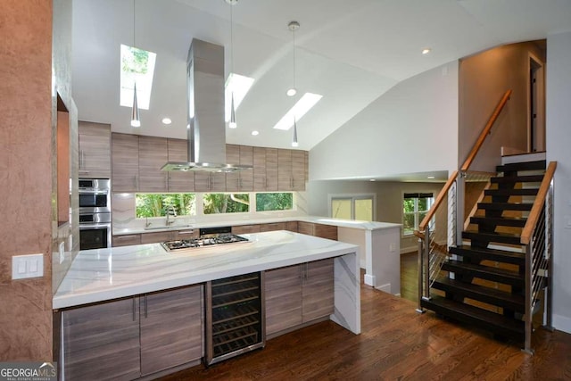 kitchen with decorative light fixtures, a skylight, wine cooler, island exhaust hood, and stainless steel appliances