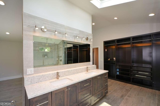 bathroom featuring vanity, hardwood / wood-style floors, a shower with shower door, and lofted ceiling with skylight