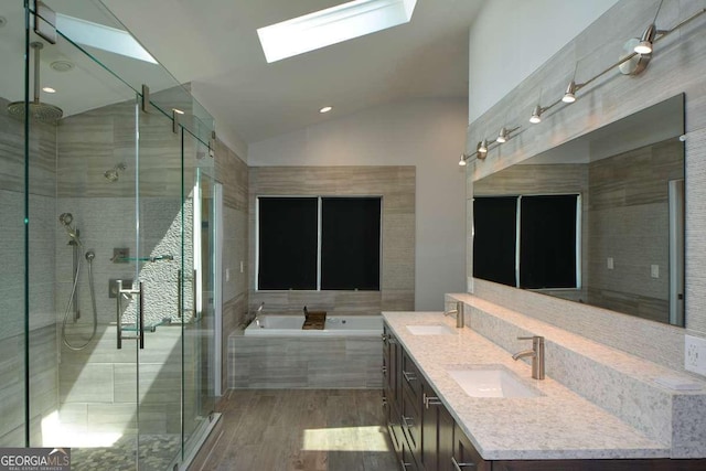 bathroom with vanity, hardwood / wood-style flooring, lofted ceiling with skylight, and shower with separate bathtub