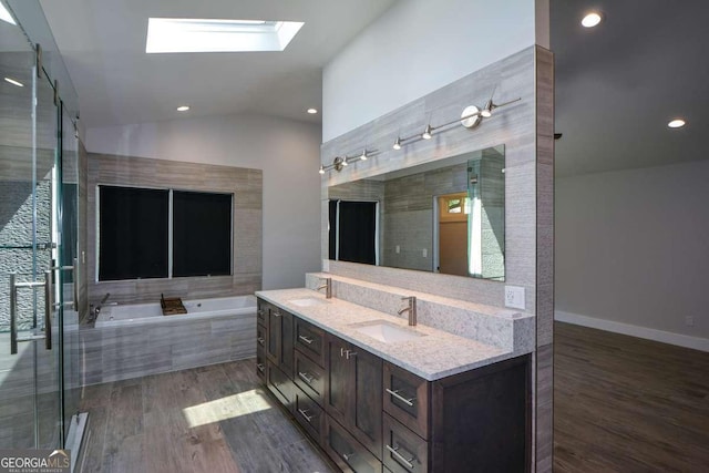 bathroom with wood-type flooring, lofted ceiling with skylight, vanity, and plus walk in shower