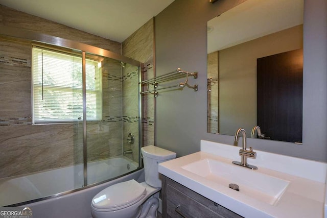 full bathroom featuring vanity, shower / bath combination with glass door, and toilet