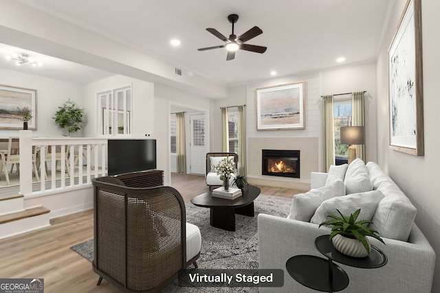 living area with recessed lighting, wood finished floors, and a glass covered fireplace