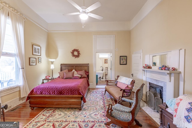 bedroom featuring ceiling fan, a premium fireplace, and light hardwood / wood-style floors