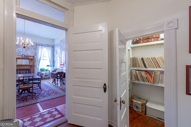 corridor with hardwood / wood-style floors and a notable chandelier