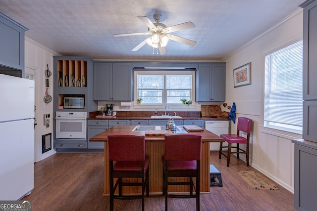 kitchen with sink, white appliances, dark wood-type flooring, gray cabinetry, and ornamental molding