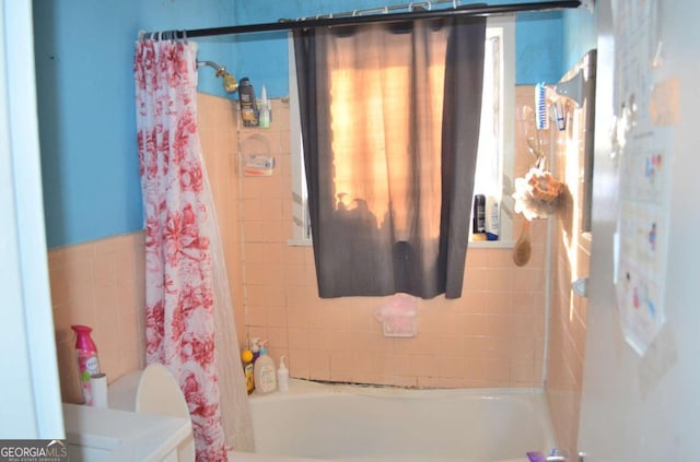 bathroom with shower / bathtub combination with curtain and tile walls