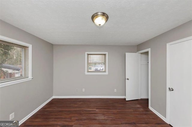 unfurnished bedroom featuring dark wood-type flooring and a textured ceiling