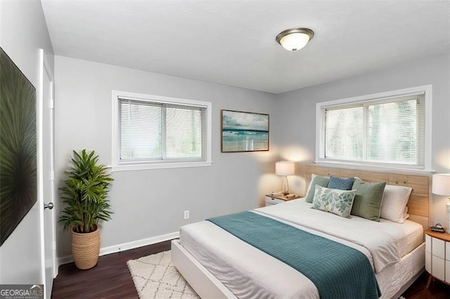 bedroom with multiple windows and dark hardwood / wood-style floors