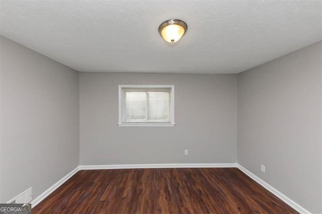 spare room with dark wood-type flooring and a textured ceiling