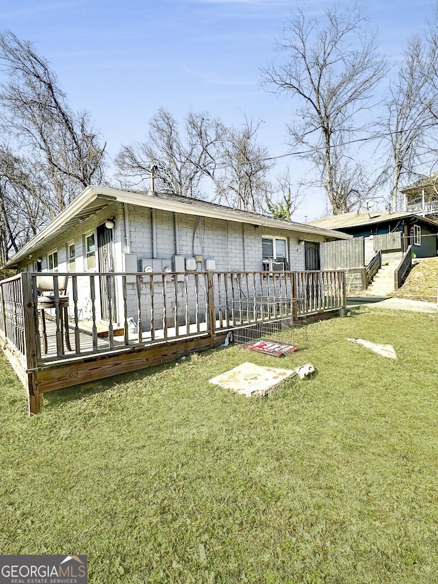 back of property featuring a wooden deck and a lawn