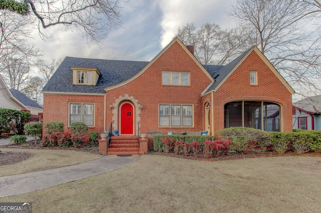 tudor-style house featuring a front lawn