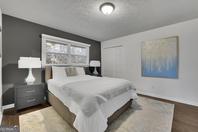 bedroom featuring a closet, dark hardwood / wood-style flooring, and a textured ceiling