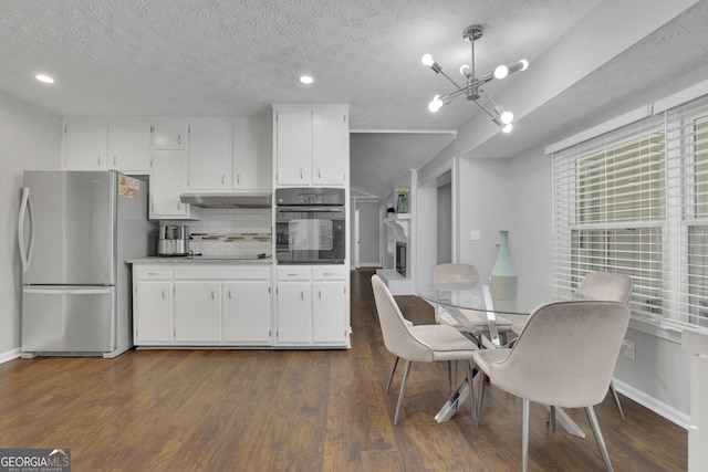 kitchen with stainless steel refrigerator, oven, white cabinets, and pendant lighting