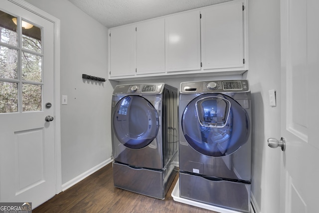 clothes washing area with a textured ceiling, dark hardwood / wood-style floors, cabinets, and washing machine and clothes dryer