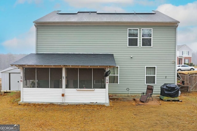 rear view of property featuring a yard, a sunroom, and solar panels