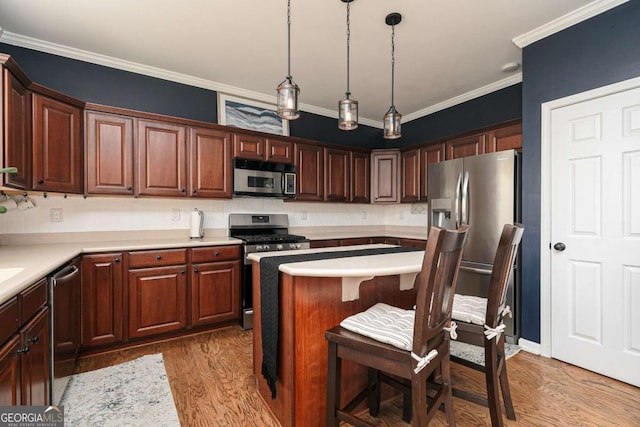 kitchen featuring crown molding, decorative light fixtures, a breakfast bar, and appliances with stainless steel finishes