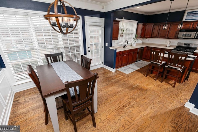 dining room featuring an inviting chandelier, ornamental molding, light hardwood / wood-style floors, and sink