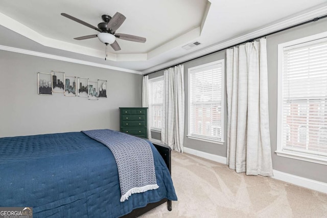 carpeted bedroom featuring ornamental molding, ceiling fan, and a tray ceiling