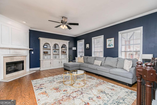 living room with ceiling fan, ornamental molding, a premium fireplace, and hardwood / wood-style floors