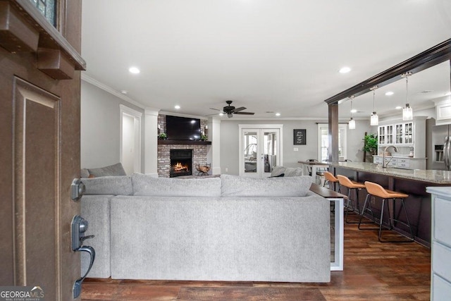 living room with crown molding, a brick fireplace, dark hardwood / wood-style floors, and sink