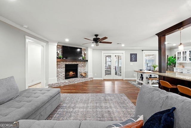 living room with ornamental molding, a brick fireplace, dark hardwood / wood-style floors, and french doors