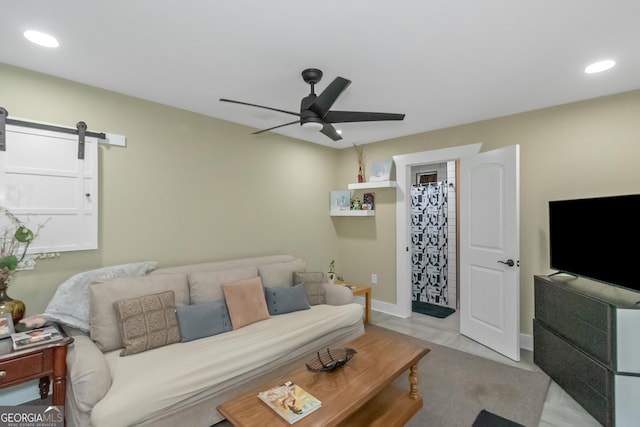 living room featuring a barn door, light wood-type flooring, and ceiling fan