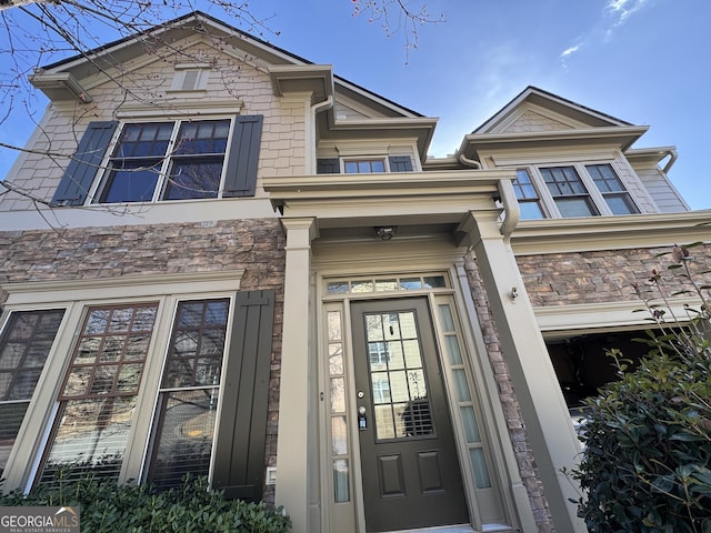 doorway to property featuring a garage and stone siding