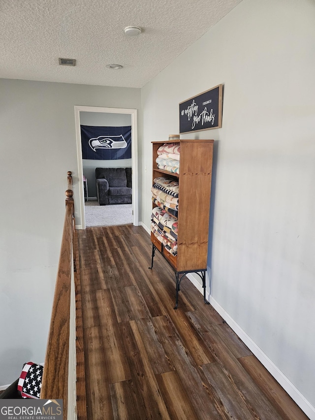 hall with dark hardwood / wood-style floors and a textured ceiling