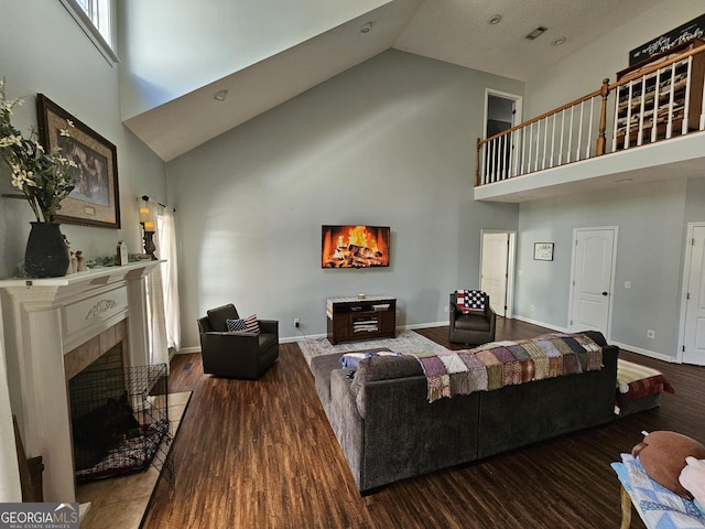 living room with a tiled fireplace, dark hardwood / wood-style floors, and a high ceiling