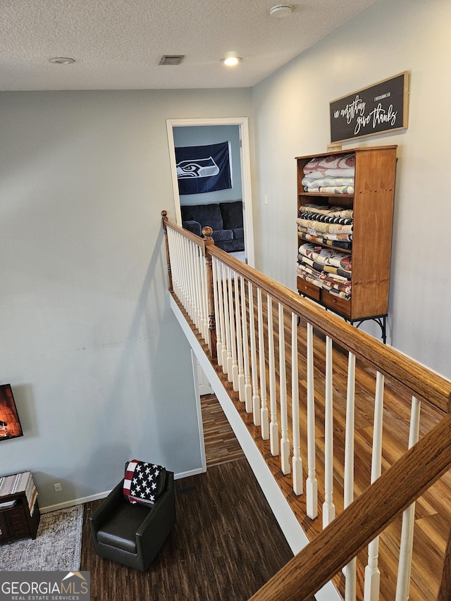 staircase with hardwood / wood-style flooring and a textured ceiling