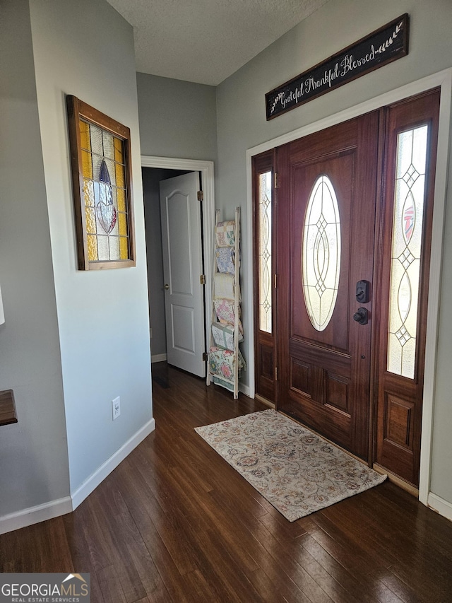 foyer entrance with dark wood-type flooring and a textured ceiling