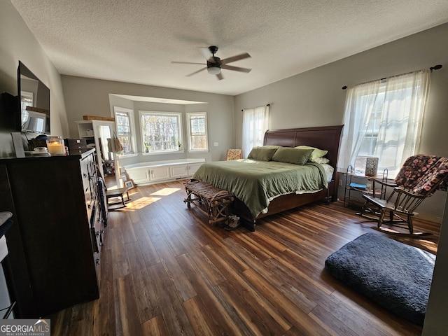 bedroom with ceiling fan, dark hardwood / wood-style floors, and a textured ceiling